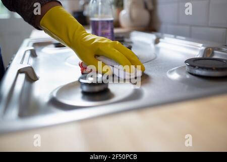 Nahaufnahme Frau in Gummihandschuhe Reinigung Küchenherd mit Lappen Stockfoto