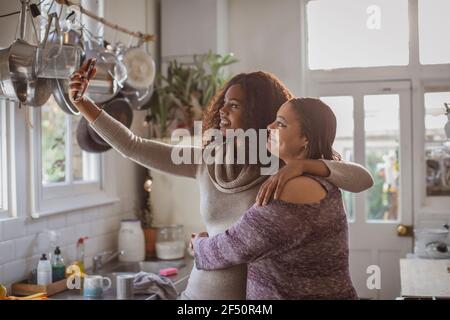Mutter und Tochter nehmen Selfie in der Küche Stockfoto