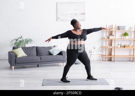 Volle Länge erfreut afroamerikanischen Übergewicht Frau in Sportbekleidung Training zu Hause Stockfoto