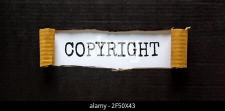 Copyright-Symbol. Das Wort 'Copyright' erscheint hinter zerrissenem schwarzem Papier. Schöner schwarzer Hintergrund. Business, Copyright-Konzept. Speicherplatz kopieren. Stockfoto