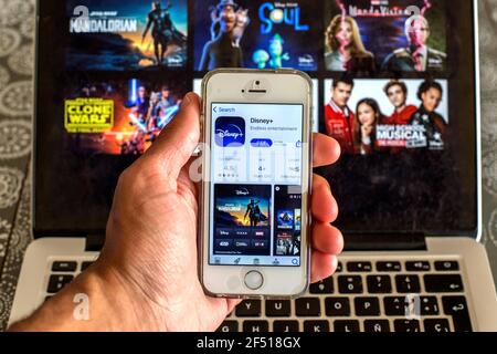 Barcelona, Katalonien, Spanien. März 2021, 23rd. In dieser Abbildung wird die Disney-App im App Store auf einem Smartphone-Bildschirm und eine Disney-Website auf einem Laptop im Hintergrund angezeigt. Quelle: Thiago Prudencio/DAX/ZUMA Wire/Alamy Live News Stockfoto