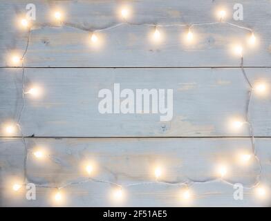 Girlande von runden weihnachtsbeleuchtung mit warmer Farbe in platziert Die Form des Rahmens auf dem hellen Hintergrund hölzern Planken Stockfoto