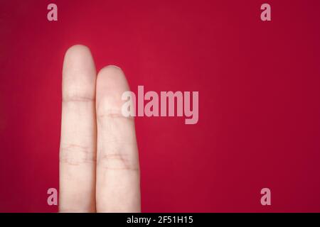 Nahaufnahme des mittleren und Zeigefingers einer Person Vor einem roten Hintergrund Stockfoto