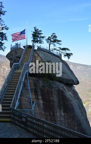 Die amerikanische Flagge weht auf dem namensgebenden Granitturm im Chimney Rock State Park außerhalb von Asheville, North Carolina. Stockfoto