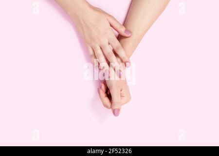 Schöne weibliche Hände auf einem rosa Hintergrund. Stockfoto