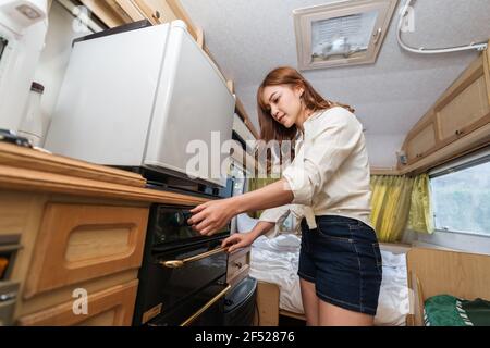 Junge Frau Kochen in der Küche eines Wohnmobil Wohnmobil van Wohnmobil Stockfoto