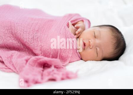 Happy neugeborenes Baby schlafen in rosa Tuch Wrap Decke auf Ein Bett Stockfoto