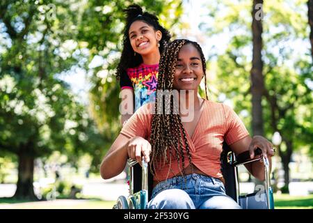 Frau im Rollstuhl im Park mit ihrer Tochter. Stockfoto