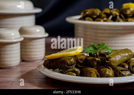 Draufsicht, Teller mit köstlichen, gefüllten Traubenblättern namens Dolma, hergestellt aus Reben mit Reis, Fleisch und Gewürzen. Stockfoto