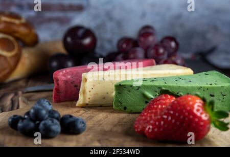 Draufsicht auf verschiedene holländische und niederländische Käsesorten auf dem Teller und Brot und Obst auf Holzkulisse. Stockfoto