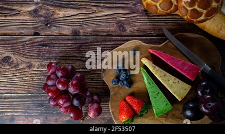 Draufsicht auf verschiedene holländische und niederländische Käsesorten auf dem Teller und Brot und Obst auf Holzkulisse. Stockfoto