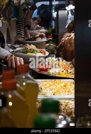 Hände, die nach Speisen in arabischem Buffet mit orientalischem Buffet greifen, Sideboard, das Mahlzeiten serviert, in denen Essen in einem öffentlichen Bereich, in dem das din platziert wird, platziert wird Stockfoto