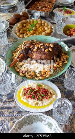 Gegrillter Lammschenkel, auf Freekeh oder Frikeh - Hartweizen - und Nüsse, Seitenansicht auf einem Esstisch. Stockfoto