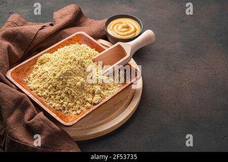 Senfpulver Nahaufnahme auf dunkelbraunem Hintergrund. Kochkonzept. Stockfoto