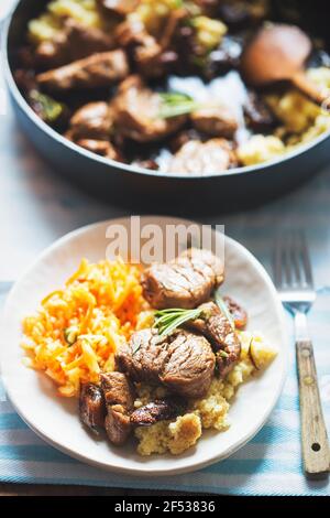 Teriyaki Schweinelenden in Whiskey, Kaffee und Rosmarinsauce, serviert mit Couscous und Salat Stockfoto