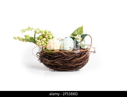 Vogelnest mit Ostereiern und künstlichem Grün. Ostertisch oder Party Dekoration. Kleine Vögel nisten mit Zweigen. Weiche blaue und gelbe Polka tun Stockfoto