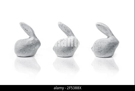 Drei kleine Steinkaninchen. Seitenprofil von kleinen entzückenden einfachen Osterhasen. Tischdekoration mit Tier- oder Ostermotiven. Isoliert auf Weiß. Stockfoto