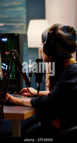 Frau Streamer Überprüfung Ton mit professionellen Mixer für Streaming-Videospiele in Gaming-Home-Studio. Pro Gamer spielen Ego-Shooter-Videospiele im Gespräch mit Teamkollegen im offenen Chat Stockfoto