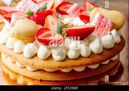 Biskuitkuchen mit Erdbeeren, rosa Milchschokolade, Silberstreuseln, Vanillecreme und herzkranken Keksen aus nächster Nähe. Sommer süßes Dessert für bi Stockfoto
