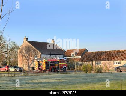 März - Feuerwehrmaschine in Anwesenheit eines ländlichen Bauernhauses in Somerset, Stockfoto