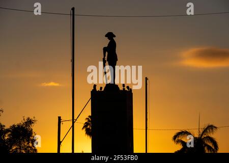 Kriegsdenkmal mit einem Soldaten und einem umgedrehten Gewehr in Charters Towers, Queensland, Australien, das vor einem goldenen Sonnenaufgang steht. Stockfoto