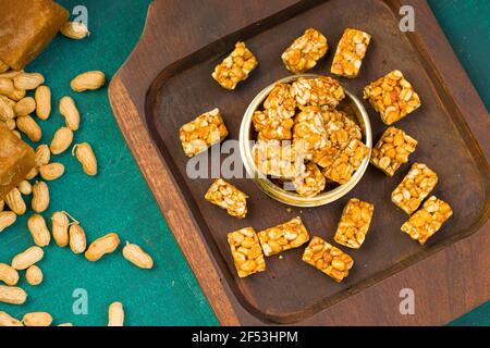 Peanut Bar, knusprig süße Peanut Bar, die sehr gesunde Snack, arrangiert In einer Holzunterlage mit etwas Erdnuss und Zacken Die dunkelgrüne Textur zurück Stockfoto