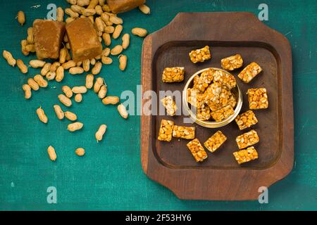 Peanut Bar, knusprig süße Peanut Bar, die sehr gesunde Snack, arrangiert In einer Holzunterlage mit etwas Erdnuss und Zacken Die dunkelgrüne Textur zurück Stockfoto