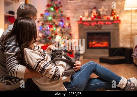 Romantisches Paar mit schottischer Falte, das Weihnachten vor einem warmen Kamin genießt. Stockfoto