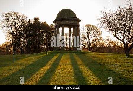 Duddingston, Edinburgh, Schottland, UK Wetter. 24th. März 2021. Sonnenschein bei 10 Grad auf dem Golfplatz. Das charakteristische Loch ist das 426-Yard 13th namens "Temple" - benannt nach dem Denkmal des Duke of Abercorn, das neben dem Loch steht. Der erste Club in Duddingston gegründet, wurde der Insurance & Banking Golf Club, im Jahr 1895. ... Entworfen von Willie Park Junior, und der Kurs misst jetzt 6.525 Meter. Im Bild: Der frühe Morgensonne wirft einen Schatten der Säulen des Denkmals auf das Gras. Quelle: Arch White/Alamy Live News. Stockfoto