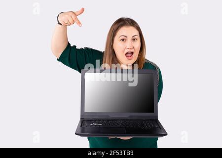 Kaukasische dicke Frau mit Laptop-Computer und Zeigefinger auf den Bildschirm. Remote Work und Online Business Konzept. Stockfoto