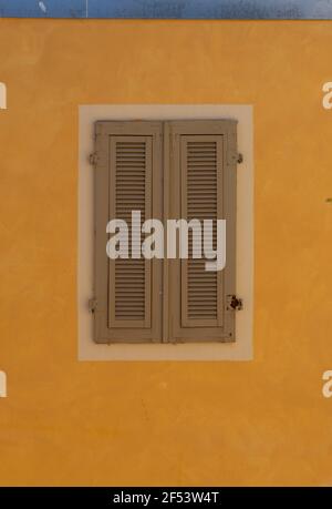 Fenster geschlossen mit Holz auf einer gelben Tonwand orange Farbe. Stockfoto