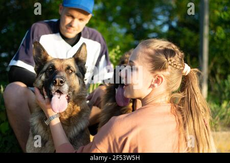 Aktive Familie, Fitness-Paar, Pet Love, Dog Training, beste Hunderassen für die Familie. Junge Sport Paar zu Fuß mit zwei Schäferhunde im Freien Stockfoto