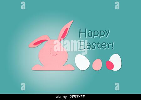 Osterkreativität. Schneiden Sie Papier Kaninchen und Eier auf einem blauen Hintergrund, Rückansicht. Die Inschrift "Frohe Ostern". Osterkonzept. Stockfoto