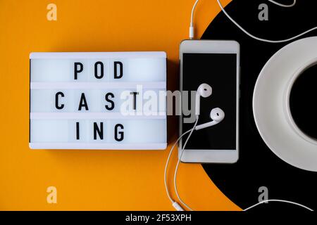 Podcasting-Schriftzug. Tasse schwarzen Kaffee auf vynil Rekord. Speicherplatz kopieren. Musik hören. Retro-Style. Mobiltelefon mit Kopfhörern. Stockfoto