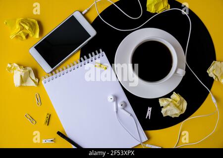 Tasse schwarzen Kaffee auf vynil Rekord. Speicherplatz für Notizbuch-Kopien. Musik hören. Retro-Style. Mobiltelefon mit Kopfhörern. Stockfoto