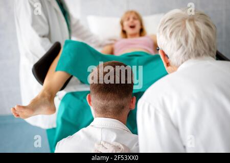 In dem Krankenhaus treibt die Frau in der Arbeit die Geburt voran, Geburtshelfer helfen Stockfoto