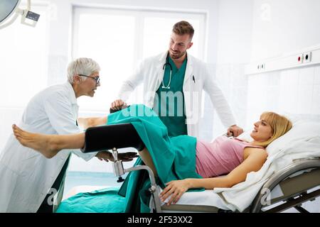 In dem Krankenhaus treibt die Frau in der Arbeit die Geburt voran, Geburtshelfer helfen Stockfoto