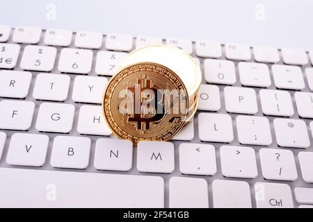 Bitcoins auf einer weißen Tastatur auf einem Tisch Stockfoto
