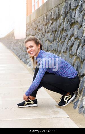 Ganzkörper-Porträt der athletischen Frau binden Sneaker auf Bürgersteig Stockfoto