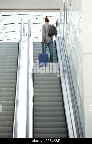 Porträt eines Mannes, der auf einer Rolltreppe mit Reisetaschen steht Stockfoto