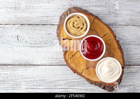 Set von drei Arten von klassischen Saucen auf Holzbrett. Mayonnaise Ketchup Senf Stockfoto