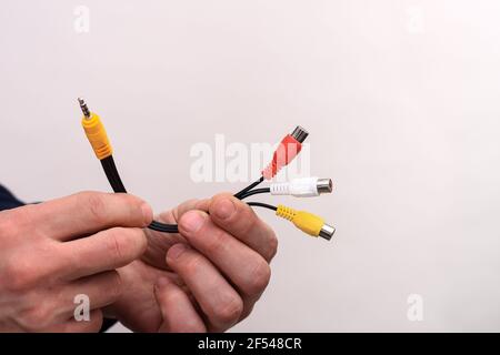 Audio-Video-Kabel RCA-Buchse in den Händen eines Mannes auf weißem Hintergrund. Stockfoto
