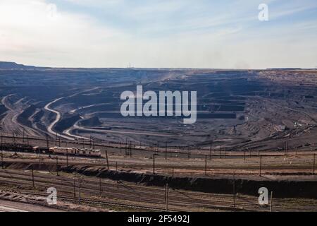 Tagebaugewinnung von Kohle im Steinbruch "Bogatyr", Ekibastuz, Kasachstan. Bagger, Bagger und Zug. Panoramablick. Hellblauer Himmel. Stockfoto