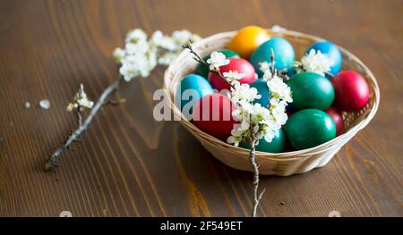 Festliche bunte Ostereier mit Frühlingsblumen, Osterfesttagsdekoration mit handbemalten Ostereiern und Frühlingsblütenzweigen Stockfoto