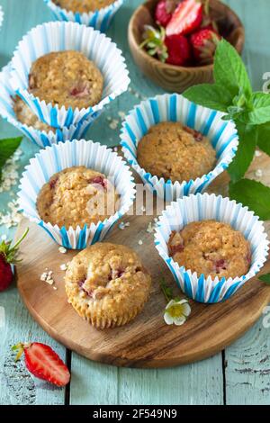 Gesunde hausgemachte Kuchen, Sommer Dessert. Glutenfreie Erdbeer Haferflocken Muffins und frische Erdbeeren auf einem rustikalen Holztisch. Stockfoto