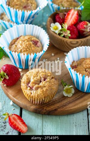 Gesunde hausgemachte Kuchen, Sommer Dessert. Glutenfreie Erdbeer Haferflocken Muffins und frische Erdbeeren auf einem rustikalen Holztisch. Stockfoto