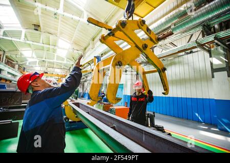 Ekibastuz, Region Pavlodar, Kasachstan Mai 28 2012: Werkstatt für den Bau von Schienenwagen. Zwei Arbeiter und Kran mechanische Hand. Stockfoto