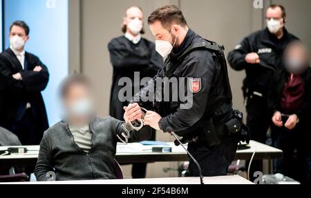 Oldenburg, Deutschland. März 2021, 24th. Ein Gerichtsbeamter öffnet die Handschellen eines Angeklagten Fahrers vor Beginn des Prozesses in der Weser-Ems-Halle, wo der Prozess wegen der vielen Beteiligten verlegt wurde. Die Staatsanwaltschaft wirft der mutmaßlichen Bande vor, in insgesamt 510 Akten zwischen Januar 2018 und August 2020 bei einem Futtermittelunternehmen in Essen (Oldenburg) Lastwagen zum Getreidetransport eingesetzt zu haben. Kredit: Hauke-Christian Dittrich/dpa - ACHTUNG: Person(en) und Namensschilder der Angeklagten wurden aus rechtlichen Gründen pixeliert/dpa/Alamy Live News Stockfoto
