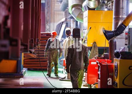 Ekibastuz, Region Pavlodar, Kasachstan-28. Mai 2012: Werkstatt für Automobilbau. Schweißer und Arbeiter verschwommen. Absaughaube rechts Stockfoto