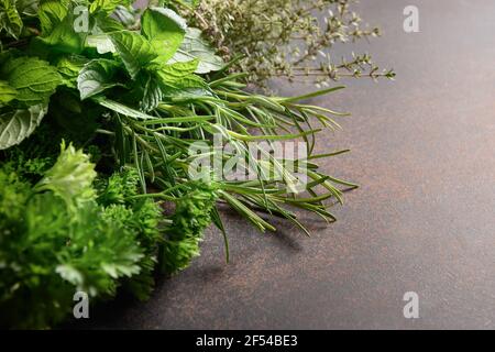 Hausgemachte frische Petersilie, Minze, Thymian, Rosmarin auf braunem Hintergrund. Nahaufnahme. Speicherplatz kopieren. Stockfoto